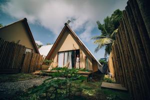 a small house with a fence and a palm tree at Cabana Gameleira - Viagem Inspirada in Fernando de Noronha