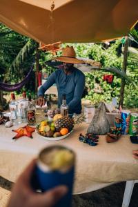 um homem usando um chapéu sentado à mesa com comida em Cabana Gameleira - Viagem Inspirada em Fernando de Noronha