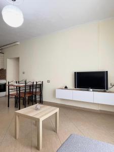 un salon avec une table et une télévision au mur dans l'établissement 3S Apartments, à Gjirokastër