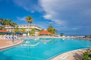 a swimming pool at a resort with palm trees and the ocean at Catalonia Montego Bay - All Inclusive in Montego Bay