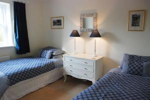 a bedroom with two beds and a dresser with a lamp at Rose Cottage, Chipping Campden in Chipping Campden +3 photos