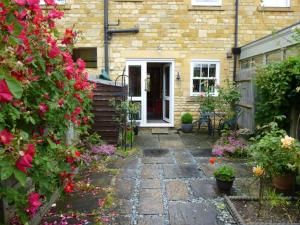 a stone walkway leading to a house with flowers at Rose Cottage, Chipping Campden in Chipping Campden