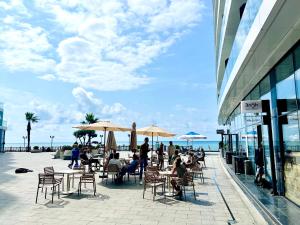 a group of people sitting at tables with umbrellas near the beach at Luxury apartment in Batumi view with sea view in Batumi