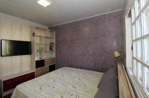 a small bedroom with a bed and a tv at Casa confortável e aconchegante in Bento Gonçalves