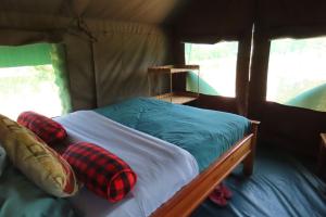 a bed in a tent with plaid pillows on it at Oseki Maasai Mara Camp in Narok