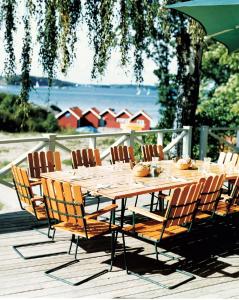 uma mesa de madeira e cadeiras sentadas num deque em Grinda Wärdshus em Grinda
