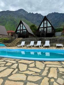 a swimming pool with lounge chairs and a house at Morning Star Kazbegi in Stepantsminda
