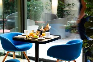 a table with a tray of food and blue chairs at H&ocirc;tel Hor Europe in Paris