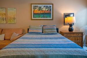 a bedroom with a bed and a lamp and a couch at Sandpiper 120B in Princeville +19 photos