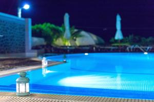 a swimming pool at night with a light in the foreground at Kalimera Hotel in Akrotiri