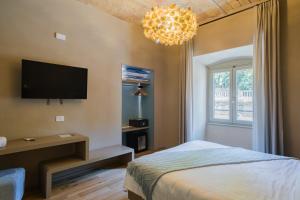 a bedroom with a bed and a tv and a chandelier at 163 BOUTIQUE HOTEL in Rome