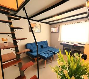 a living room with a blue chair and a desk at Laguna Lofts in Poços de Caldas