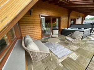 d'une terrasse avec des chaises, une table et une baignoire. dans l'établissement Chalet dans un écrin de verdure avec SPA privatif, à Jeanménil