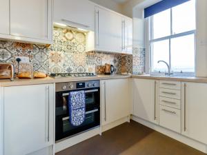a kitchen with white cabinets and a stove and a window at 2 Bed in Anstruther 80648 in Pittenweem +13 photos
