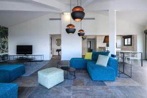 a living room with blue couches and a tv at Les Terrasses de Fromentica in Saint-Florent