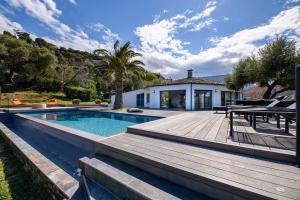 a house with a swimming pool and a wooden deck at Les Terrasses de Fromentica in Saint-Florent