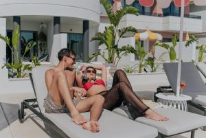 a man and a woman sitting on a beach chair at The Palms Concept Hotel Adults Only 16 Plus in Faliraki