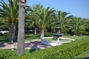 a fountain in the middle of a park with palm trees at La Corte di Opaka in Canosa di Puglia