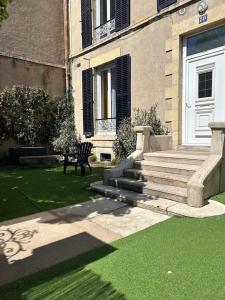 a house with stairs and a bench in the grass at Très grand appartement ancien avec petit jardin in Nevers
