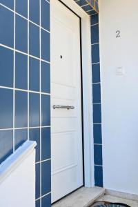 a white door in a bathroom with blue tiles at Nel Blu - Seaside Apartment in Saronida +30 photos