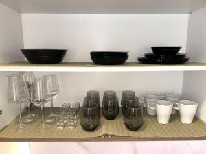 a shelf with wine glasses and plates on it at LU Apartment in Novi Sad