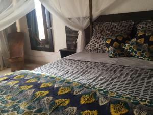a bedroom with a bed with a comforter and pillows at Warang plage villa in Mbour +28 photos