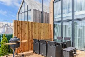 a patio with a table and chairs and a fence at Namas su PRIVAČIU BASEINU ir JACUZZI! in Palanga