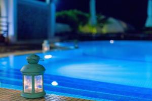 a lantern with a light next to a swimming pool at Kalimera Hotel in Akrotiri