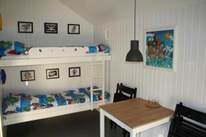 Cette chambre pour enfants comprend des lits superposés et une table. dans l'établissement Omme Å Camping & Cottages, à Sønder Omme