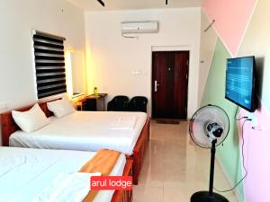 MettuppālaiyamArul Homestay的一间配有两张床和一台平板电视的酒店房间