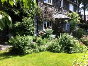 un jardin en face d'une maison en briques dans l'établissement Stockghyll Cottage, à Bowness-on-Windermere