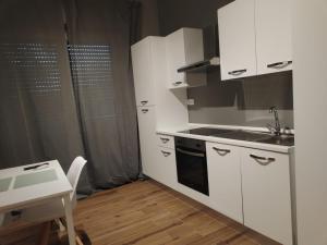 a kitchen with white cabinets and a sink and a table at HH Hermoso Housing VIA PAIETTA in Valenza