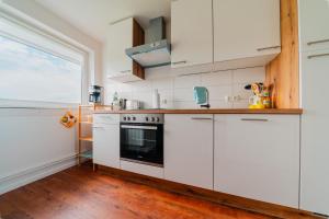 a kitchen with white cabinets and a stove at Zentrale Wohlfühlwohnung - Ideal für Ihren Urlaub oder die Geschäftsreise in Magdeburg