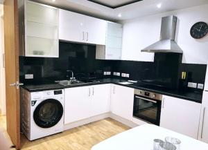 a kitchen with white cabinets and a washer and a sink at LUX Flat Marylebone in London