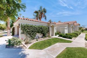 a house with a hedge in front of a yard at Riviera Manor Permit# 68147 in La Quinta