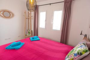 a bedroom with a pink bed with blue towels on it at Corralejo Sun 119 Fuerteventura in Corralejo
