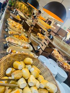 a buffet line with baskets of bread and pastries at Hotel boulevard caldas novas in Caldas Novas