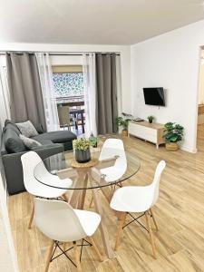 a living room with a glass table and white chairs at Coqueto con PISCINA, nuevo a 50m del mar, Parking Gratis in El Campello
