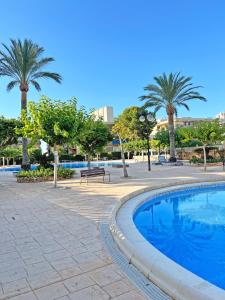 a swimming pool in a park with palm trees at Coqueto con PISCINA, nuevo a 50m del mar, Parking Gratis in El Campello