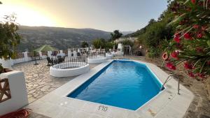 a swimming pool with tables and chairs next to at El Nogal in Bubión