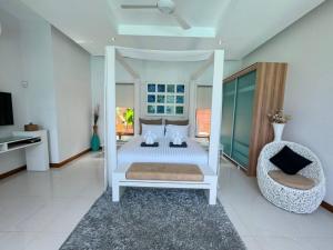 une chambre blanche avec un lit et une chaise dans l'établissement Aromdee 2 Villa by G Estate Phuket, à Ban Saiyuan (1)