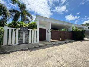 une maison blanche avec un portail et une clôture dans l'établissement Aromdee 2 Villa by G Estate Phuket, à Ban Saiyuan (1)