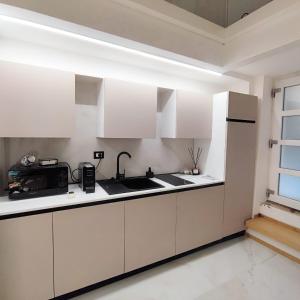Una cocina con gabinetes blancos y un fregadero. en Greta's home, en Gaeta