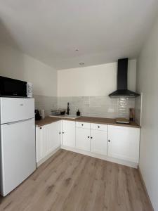 a kitchen with white cabinets and a white refrigerator at Appartement Champollion 2 in Figeac