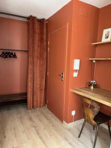 a room with orange walls and a desk and a door at Appartement Champollion 2 in Figeac
