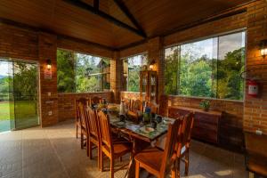 a dining room with a table and chairs and windows at Recanto Vera Lucia in Santo Amaro da Imperatriz