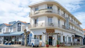 a white building with a balcony on a street at Hôtel Océan in Capbreton