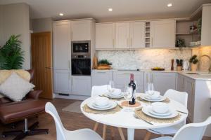 a kitchen with a white table with a bottle of wine at Y Geraint Beach Apartment Aberporth in Aberporth