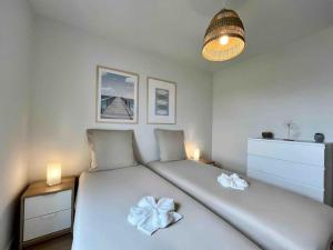 a bedroom with a white bed with a flower on it at La Maison Bleue, Jardin & Mer 300m in Dunkerque