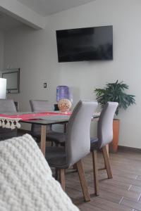 a dining room table with chairs and a television at Suites Independencia Oaxaca in Oaxaca City